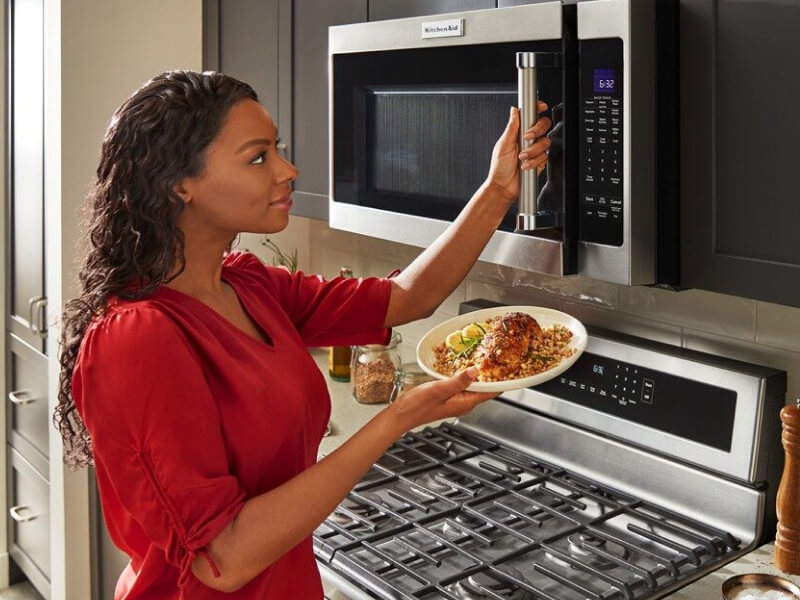 Person using a KitchenAid® microwave to warm food Person using a KitchenAid® microwave to warm food
