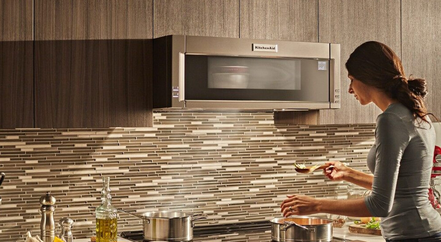 Person cooking on a stovetop with a KitchenAid® over-the-range microwave above Person cooking on a stovetop with a KitchenAid® over-the-range microwave above
