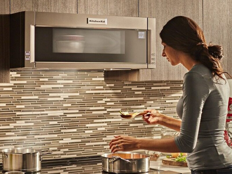 Person cooking on a stovetop with a KitchenAid® over-the-range microwave above Person cooking on a stovetop with a KitchenAid® over-the-range microwave above
