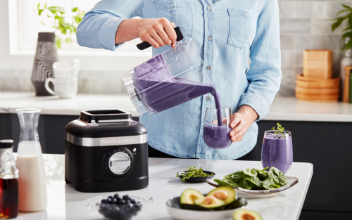 Person pouring shake from KitchenAid® blender into a glass