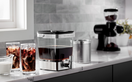 KitchenAid® cold brew coffee maker next to two glasses of cold brew with cream