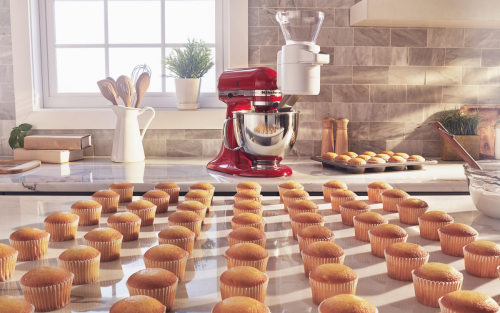 Red stand mixer behind dozens of cupcakes on the counter