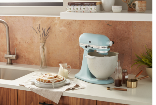 Glazed cinnamon bun beside a blue KitchenAid® Stand Mixer.