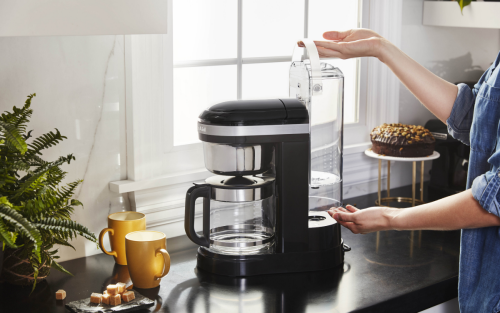 Woman removing water tank from KitchenAid® drip coffee maker