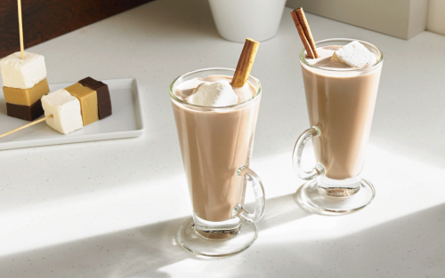 Coffee beverage in glass mugs garnished with marshmallows and cinnamon