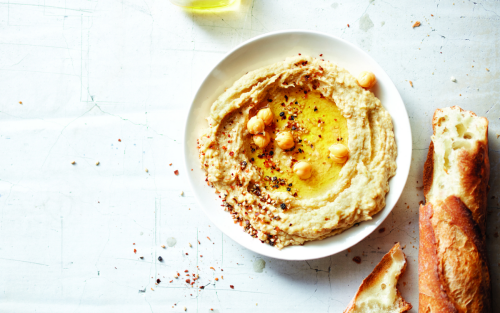 Bowl of hummus topped with whole chickpeas, oil and seasonings