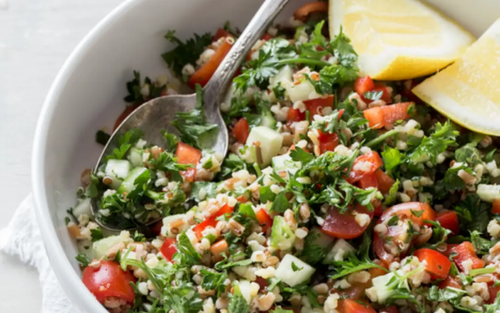 A bowl of refreshing tabouli and a serving spoon.