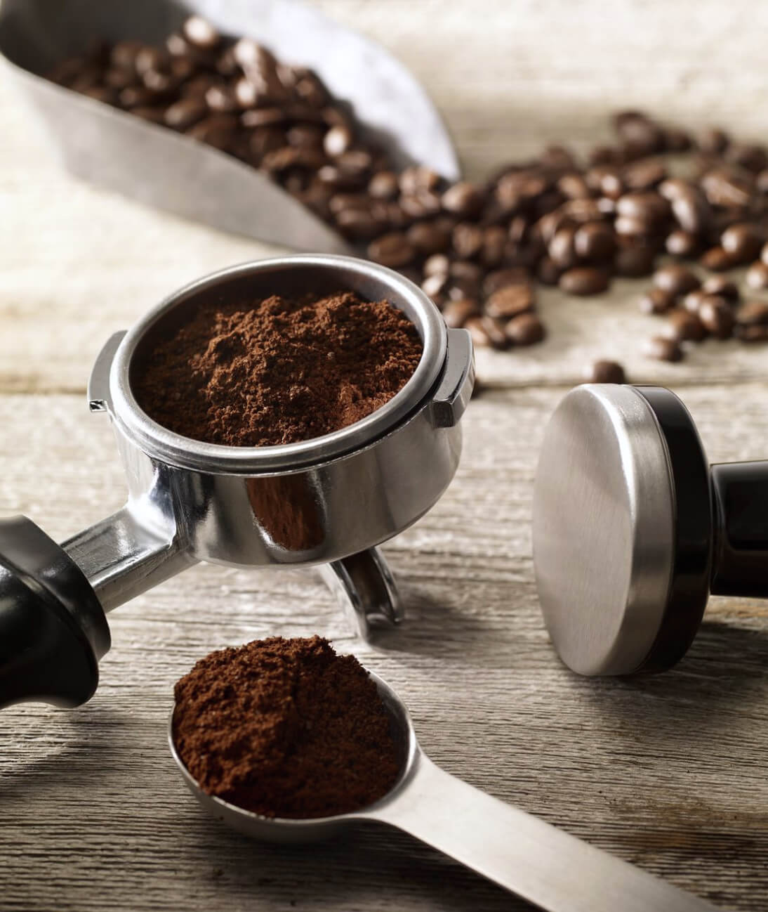 Ground espresso beans and whole espresso beans on countertop.