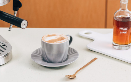 Whipped coffee in a mug on a countertop with various kitchen items