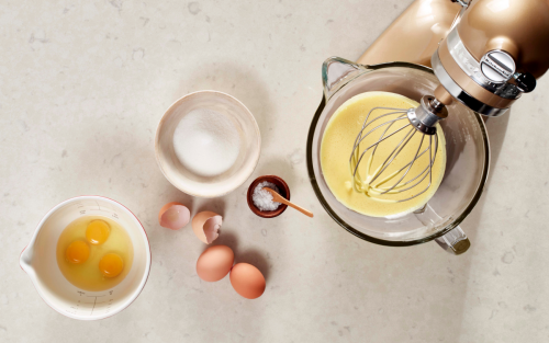 Cracked eggs, a bowl of egg yolks as well as a bowl of batter