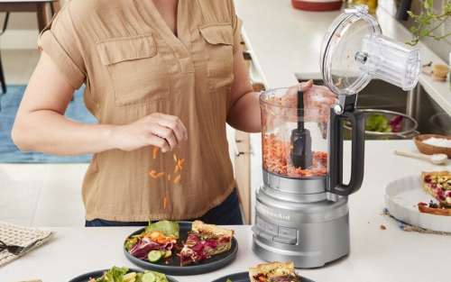 Woman shredding vegetables for a salad with a KitchenAid® food processor