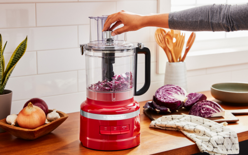 KitchenAid® food processor on a kitchen counter next to sliced purple cabbage and other vegetables