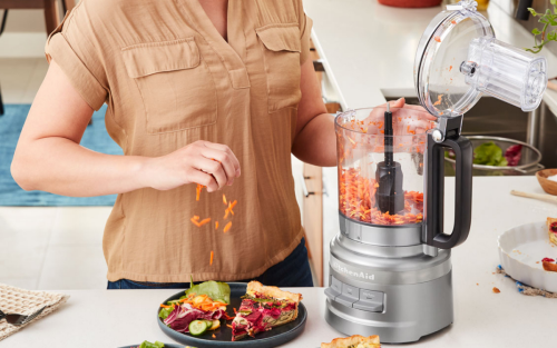 Woman shredding carrots in a KitchenAid® food processor