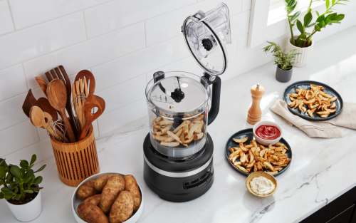 KitchenAid® food processor on a modern kitchen counter next to plates of french fries