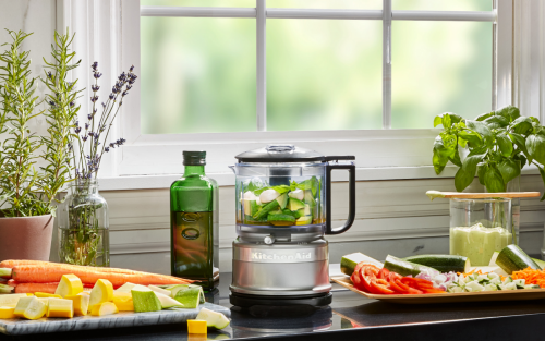 Silver food chopper filled with chopped ingredients and surrounded by chopped vegetables