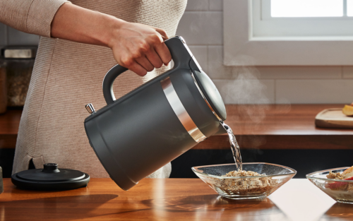 Maker pouring hot water from KitchenAid® electric kettle over bowl of oatmeal