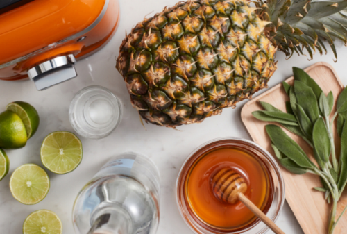 Overhead shot of KitchenAid® Honey colored blender surrounded by fresh pineapple, honey and limes.