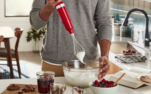 Person using red KitchenAid® immersion blender with whisk