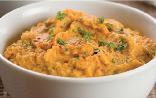 Close-up of bowl of pumpkin purée infused with spices and green garnishes