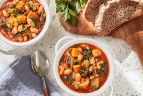 Two bowls of Pasta Fagioli sitting next to dark rye bread