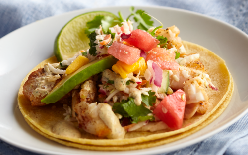 Fish taco with fruit salsa on white plate