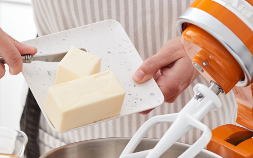 A person putting shortening in a stand mixer bowl