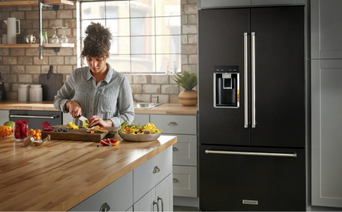 Woman chopping fruit in front of a French door refrigerator