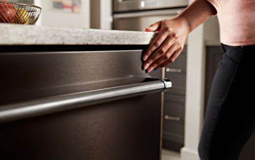 Hand closing a stainless steel dishwasher