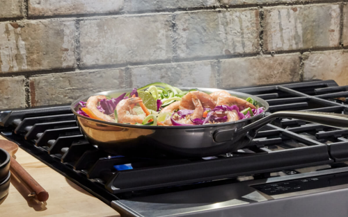 Shrimp stir fry sizzling over a gas range.