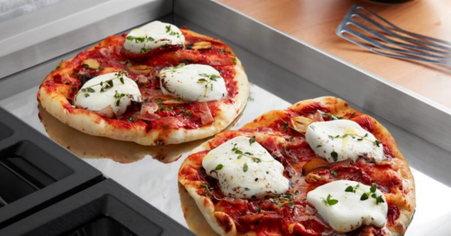 Two homemade Neapolitan pizzas cooking on a chrome electric griddle.