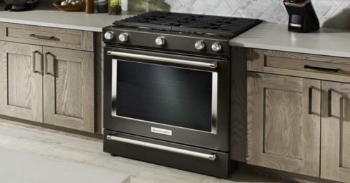 A black, self-cleaning oven installed in a clean, fully stocked kitchen.