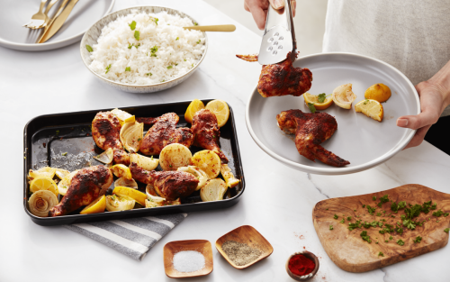 Sheet pan of roasted chicken wings and lemon wedges