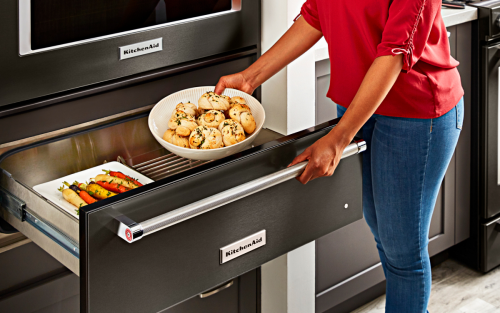 Person putting food in a warming drawer