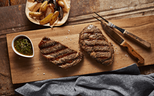 Two grilled steaks on a cutting board