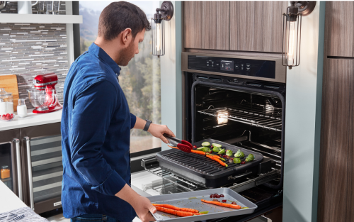 Person grilling vegetables in a KitchenAid® Smart Oven+