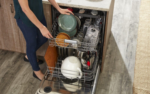 Person loading dishes into dishwasher