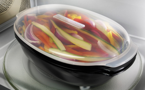 Sliced vegetables in a KitchenAid® steaming container in a microwave