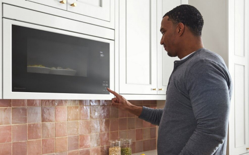 A Finger pressing a start button on a microwave