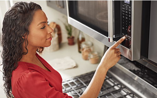 A person selecting a microwave setting on an over-the-range KitchenAid® microwave.