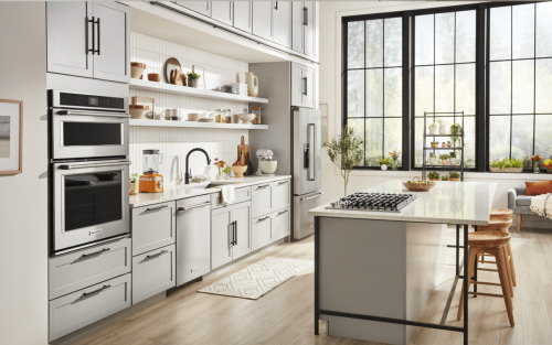 Kitchen with pale gray cabinets, white backsplash, stainless appliances.