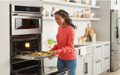 Person removing a baking sheet from a KitchenAid® double wall oven