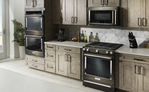 A black range, wall oven, microwave and warming drawer in a kitchen.