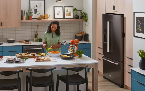 Person preparing food in a kitchen with KitchenAid® appliance suite