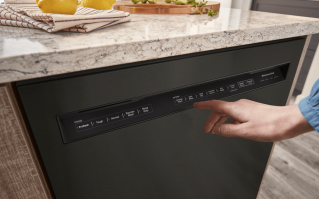 Hand touching a KitchenAid® front control dishwasher