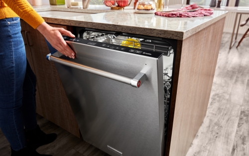 Person closing a KitchenAid® top control dishwasher