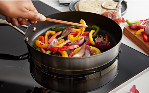 A person sauteing peppers in a pan