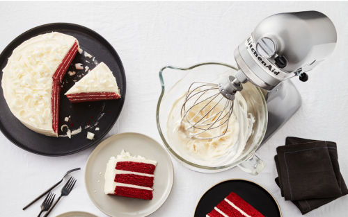 Red velvet cake next to stand mixer with frosting