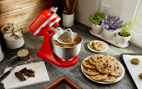 A red KitchenAid® stand mixer used to mix dough for chocolate chip cookies