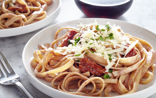 Plate of fettuccine noodles with sun dried tomatoes and parmesan