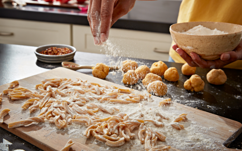 Hand sprinkling flour on fresh pasta